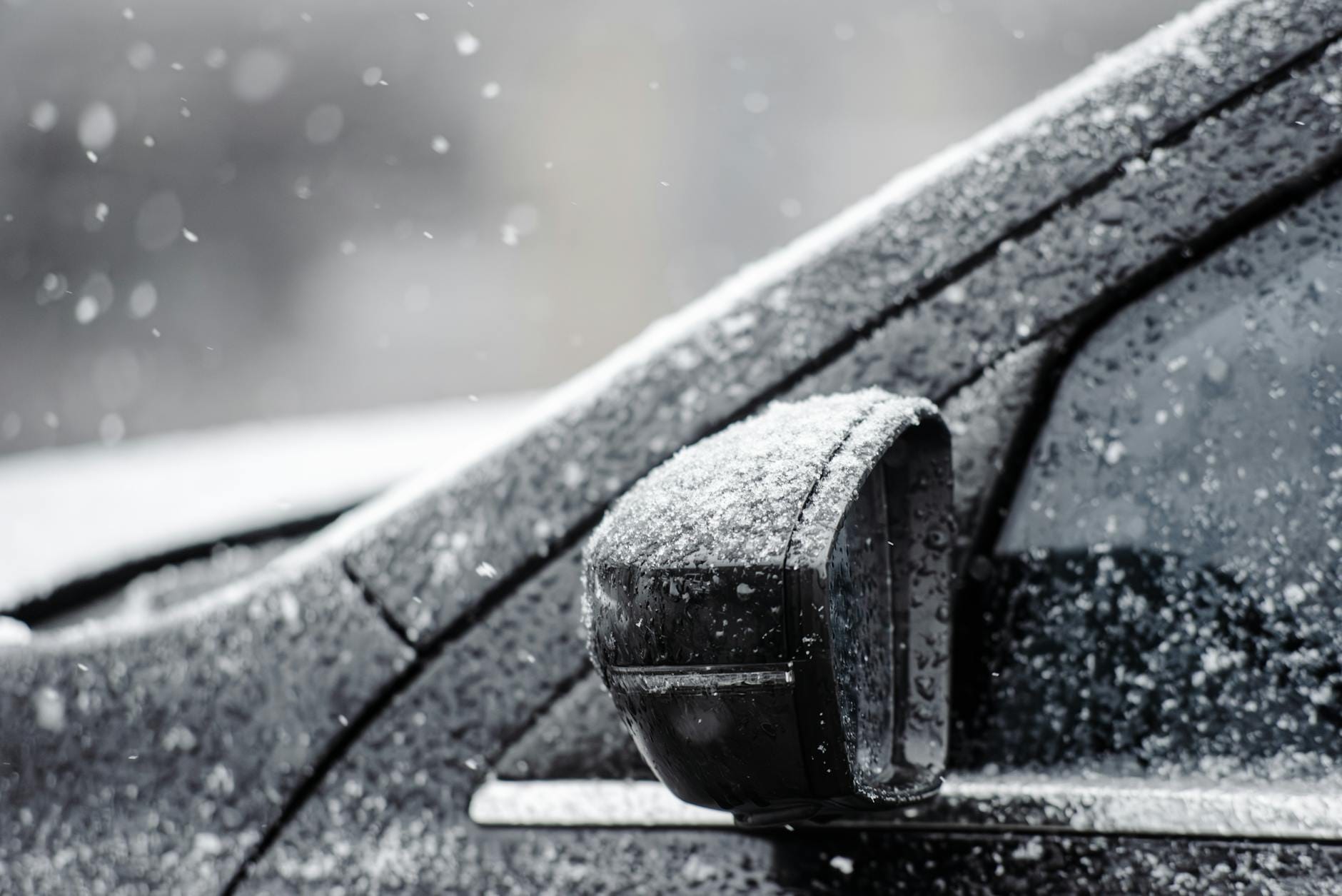 Boczny lusterk samochodu zasypany śniegiem podczas zimowej śnieżycy