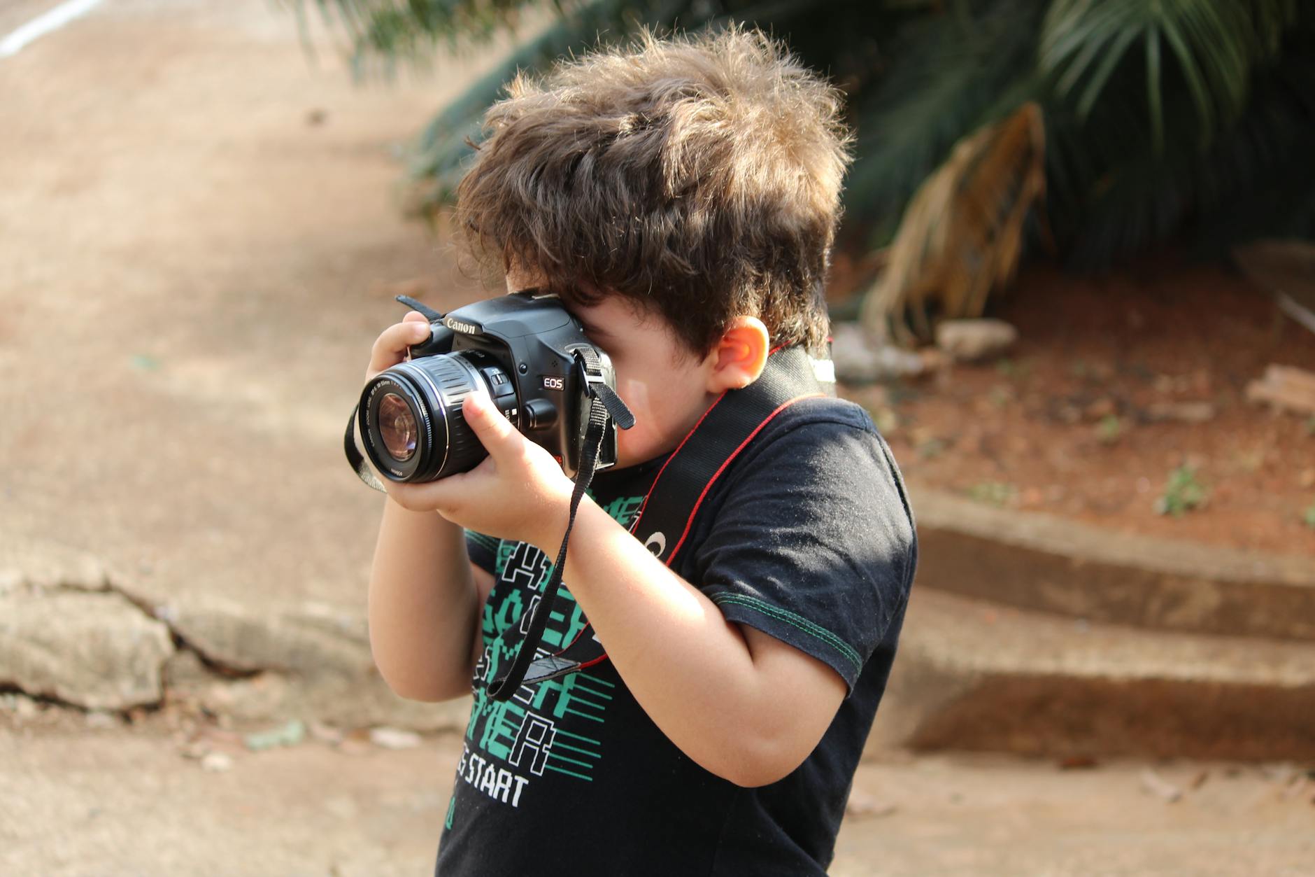 Podstawy kompozycji w fotografii – praktyczny przewodnik dla początkujących Chłopiec na dworze fotografuje lustrzanką, ucząc się kompozycji