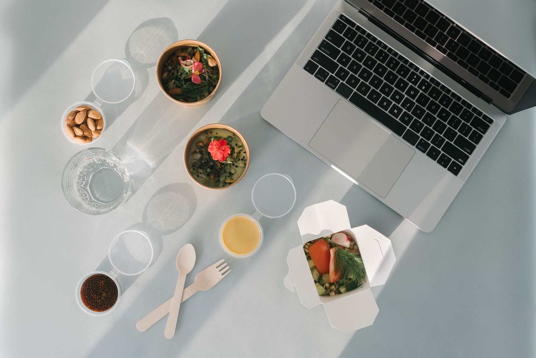 Zdrowy lunch pudełkowy przy laptopie, migdały i zupa na biurku
